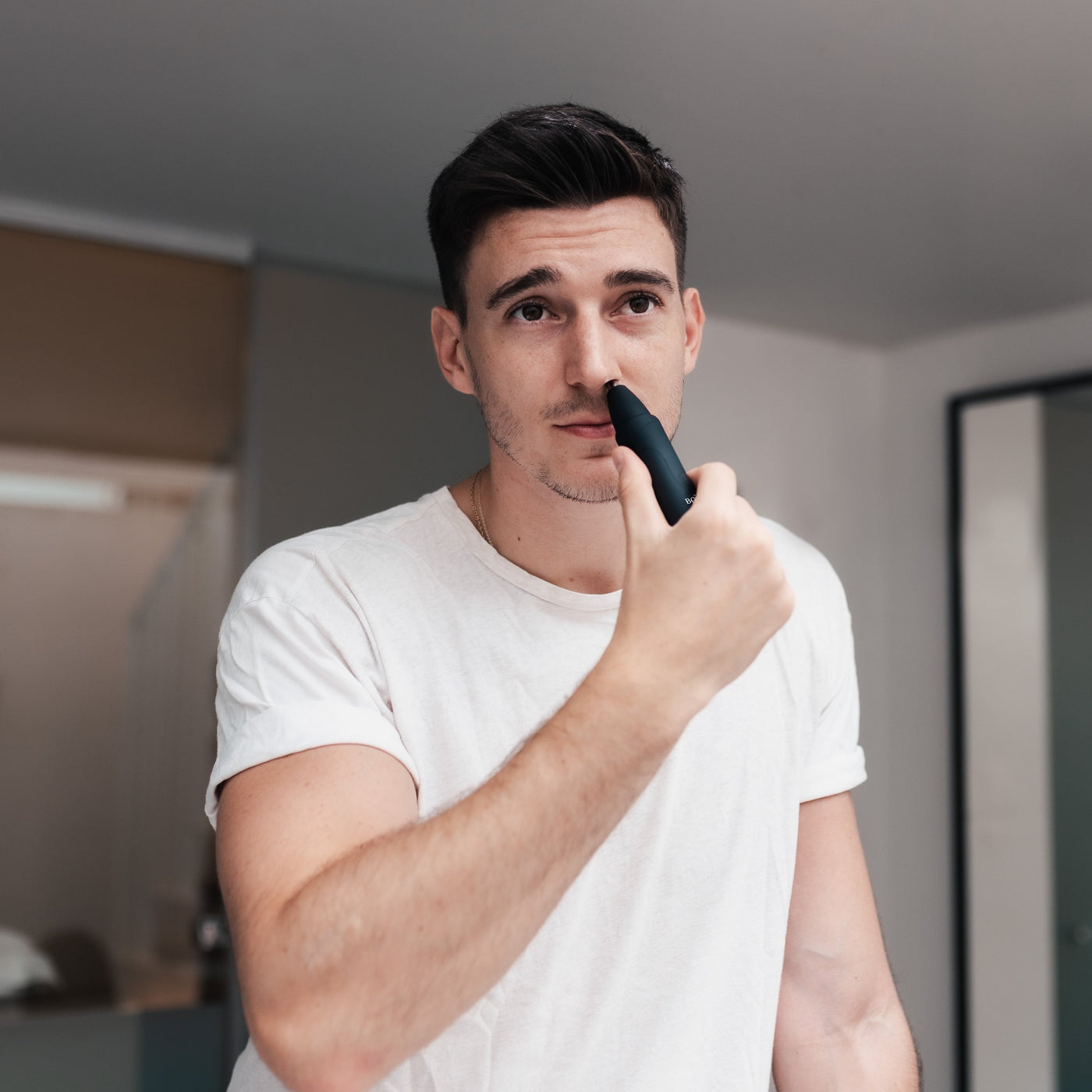man trimming nose hair in mirror